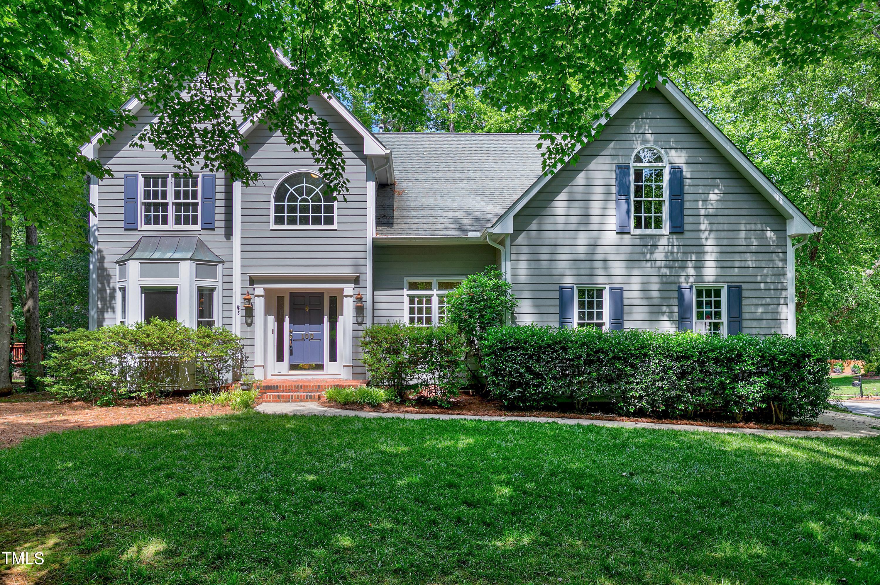 a front view of a house with a yard and trees