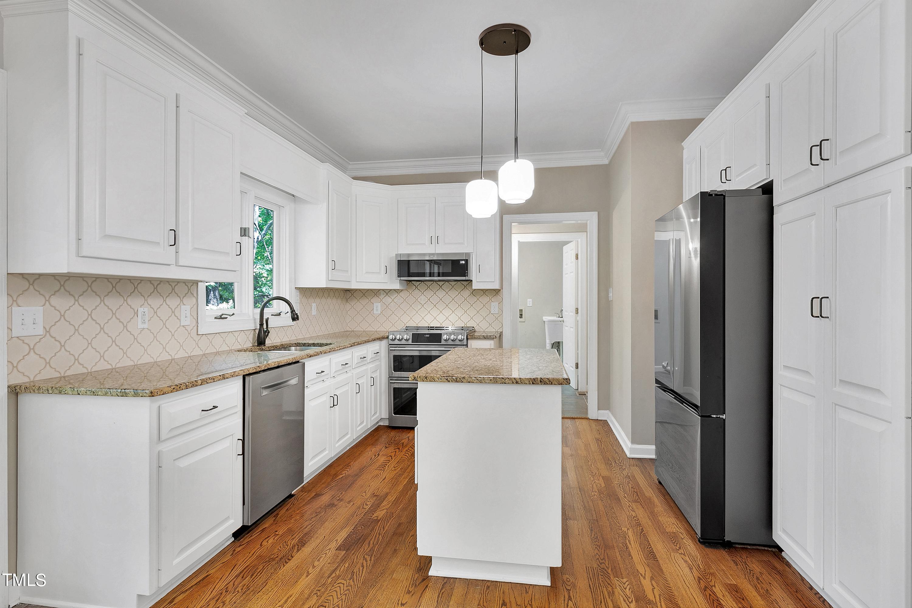 100 Buckden Place Cary, NC 27518 - Photo 15 of 70 a kitchen with stainless steel appliances granite countertop a refrigerator a sink dishwasher a stove and white cabinets with wooden floor