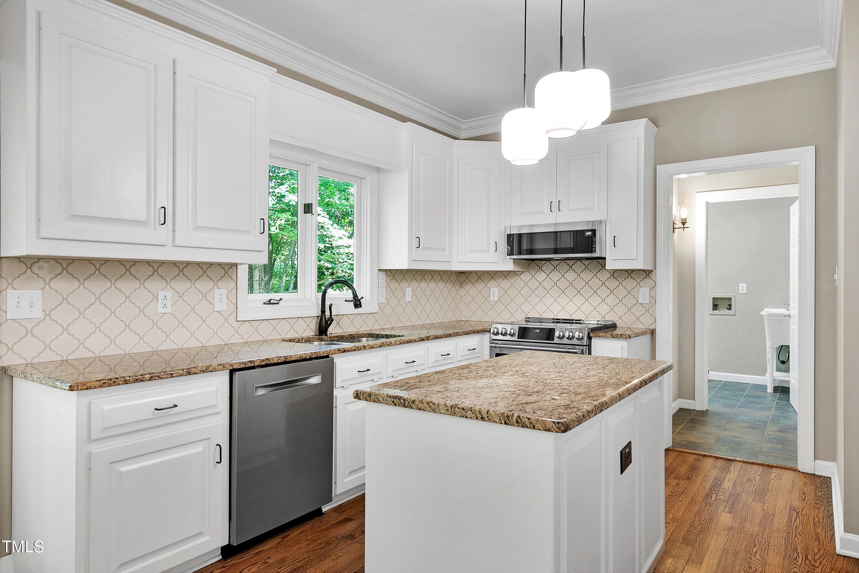 100 Buckden Place Cary, NC 27518 - Photo 16 of 70 a kitchen with kitchen island granite countertop a sink a counter space appliances and cabinets