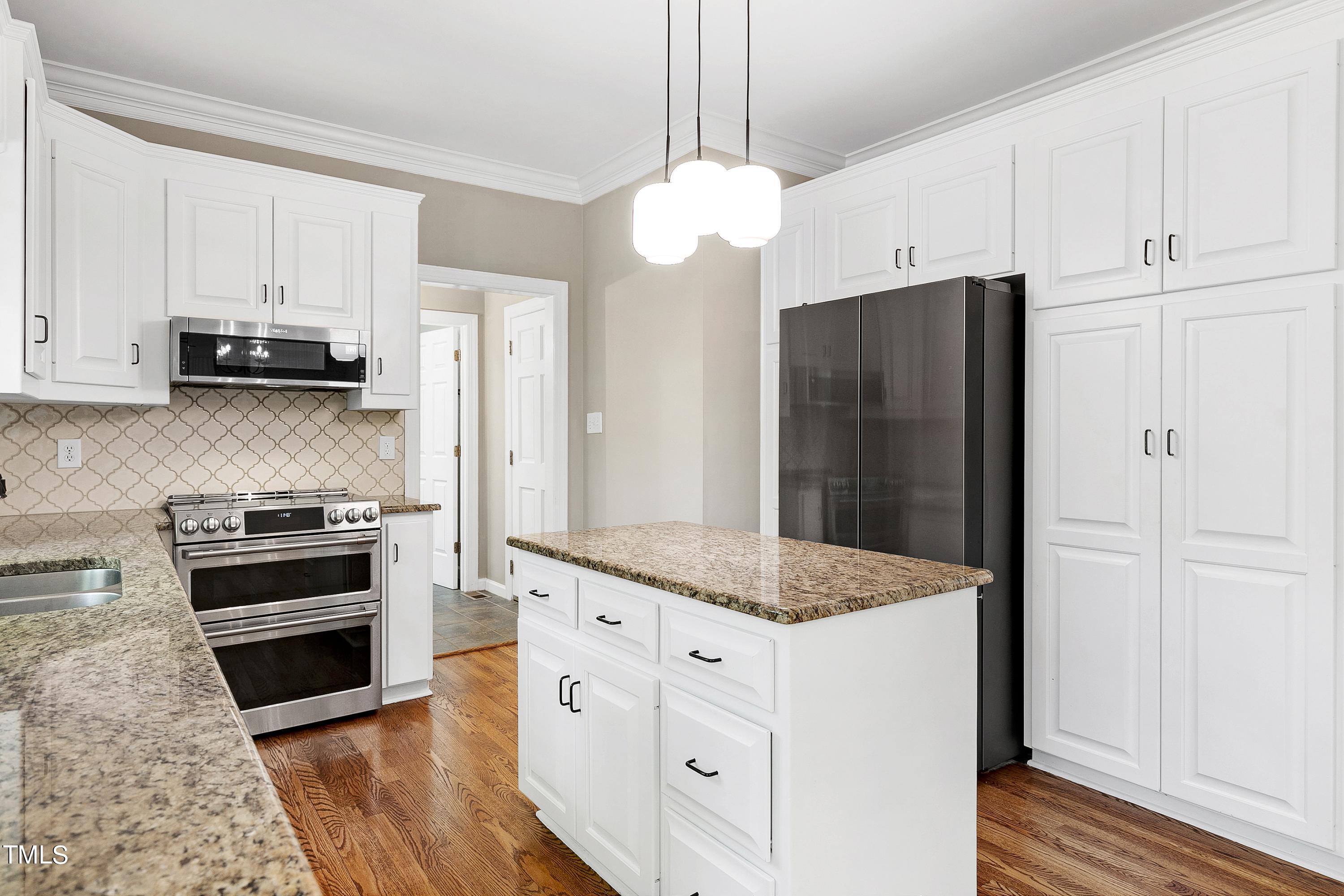 100 Buckden Place Cary, NC 27518 - Photo 17 of 70 a kitchen with stainless steel appliances kitchen island granite countertop a refrigerator and a stove top oven