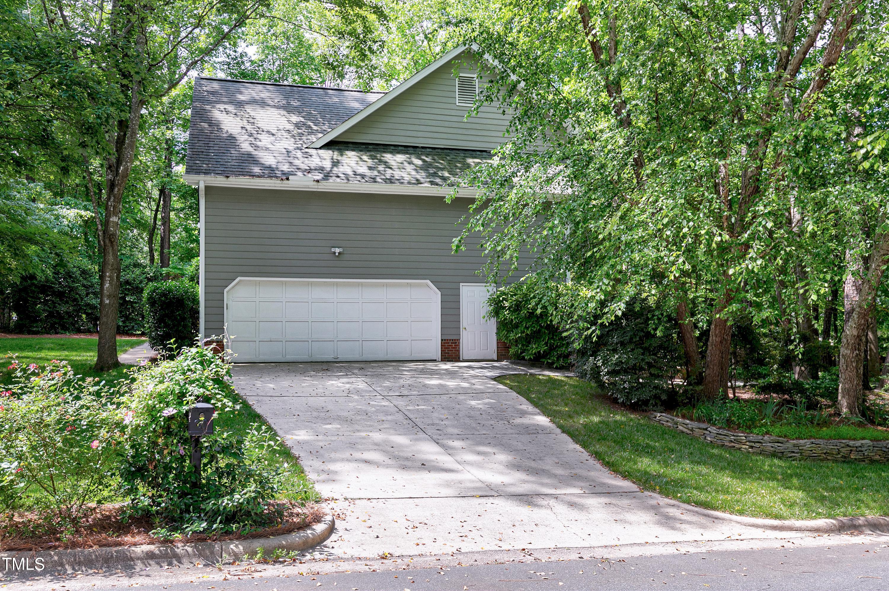 100 Buckden Place Cary, NC 27518 - Photo 56 of 70 a front view of a house with a garden and trees