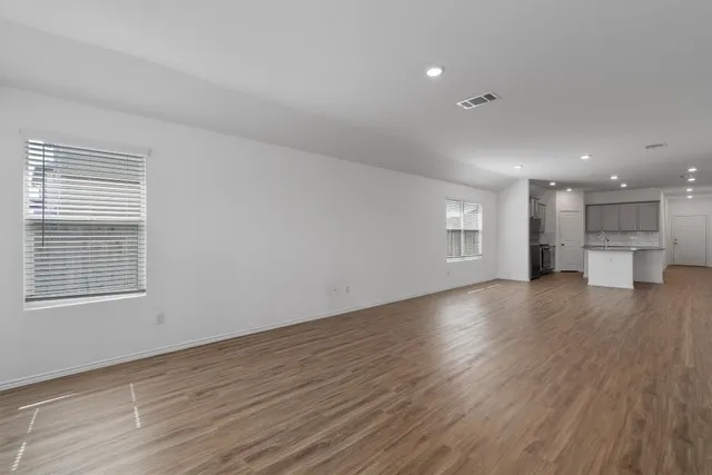 a view of empty room with wooden floor and windows