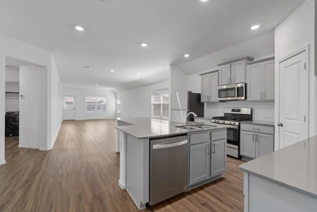 a kitchen with granite countertop a sink cabinets and stainless steel appliances