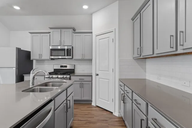 a kitchen with kitchen island granite countertop a sink dishwasher stove and refrigerator with wooden floor