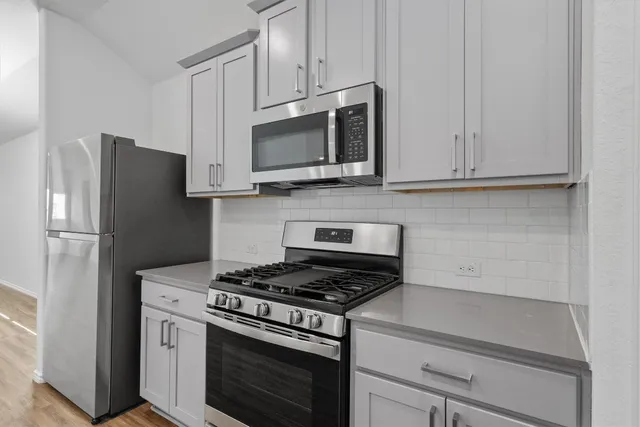 a kitchen with stainless steel appliances white cabinets and a stove a refrigerator with a white countertops