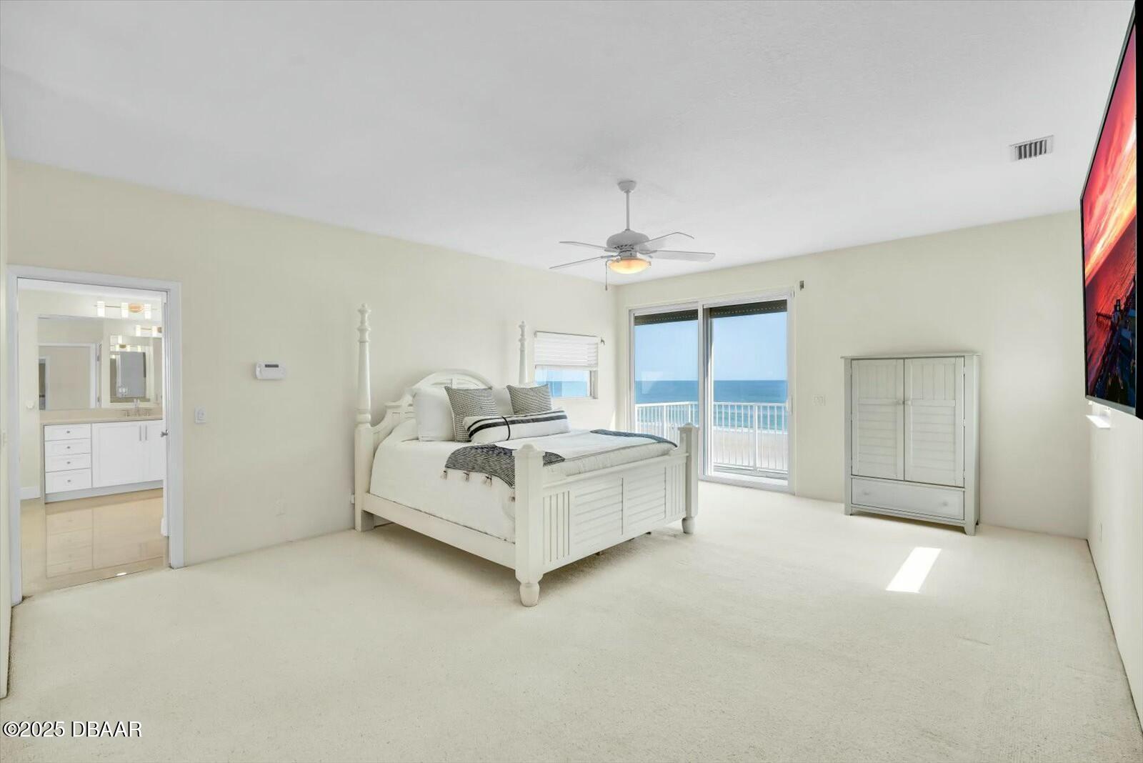 4363 South Atlantic Avenue Ponce Inlet, FL 32127 - Photo 15 of 46 a spacious bedroom with a bed and a chandelier
