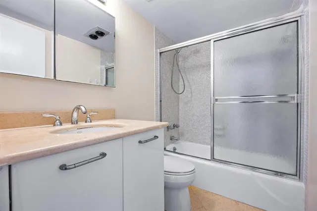 a bathroom with a shower sink vanity mirror and toilet