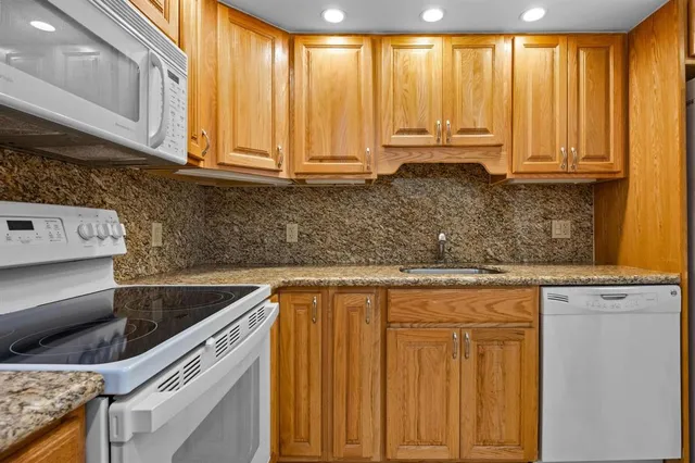 a kitchen with stainless steel appliances granite countertop a sink a stove and a microwave