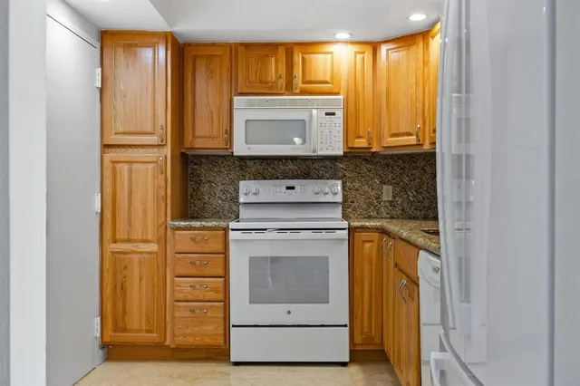 a kitchen with stainless steel appliances granite countertop a stove a sink and a refrigerator