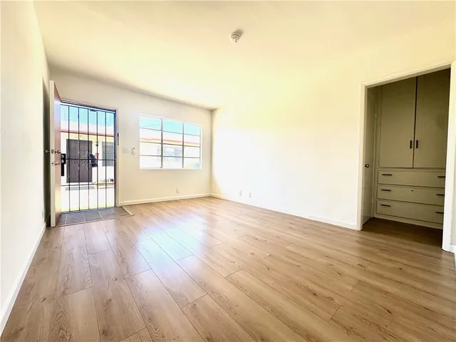 an empty room with wooden floor and windows