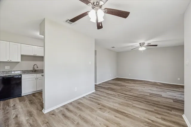 a view of a kitchen with a dishwasher a kitchen island hardwood floor and a ceiling fan