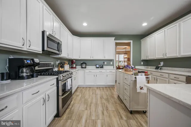 a kitchen with granite countertop a sink cabinets stainless steel appliances and a window