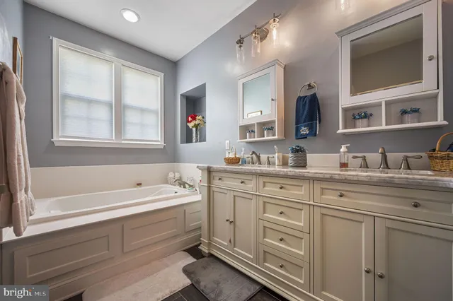 a bathroom with a granite countertop tub sink double vanity and window