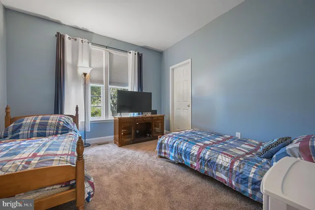 a bedroom with bed a flat tv screen and a dresser