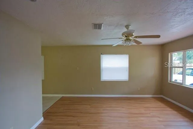 a view of empty room with wooden floor and fan
