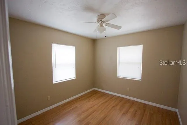 a view of an empty room with wooden floor and a window