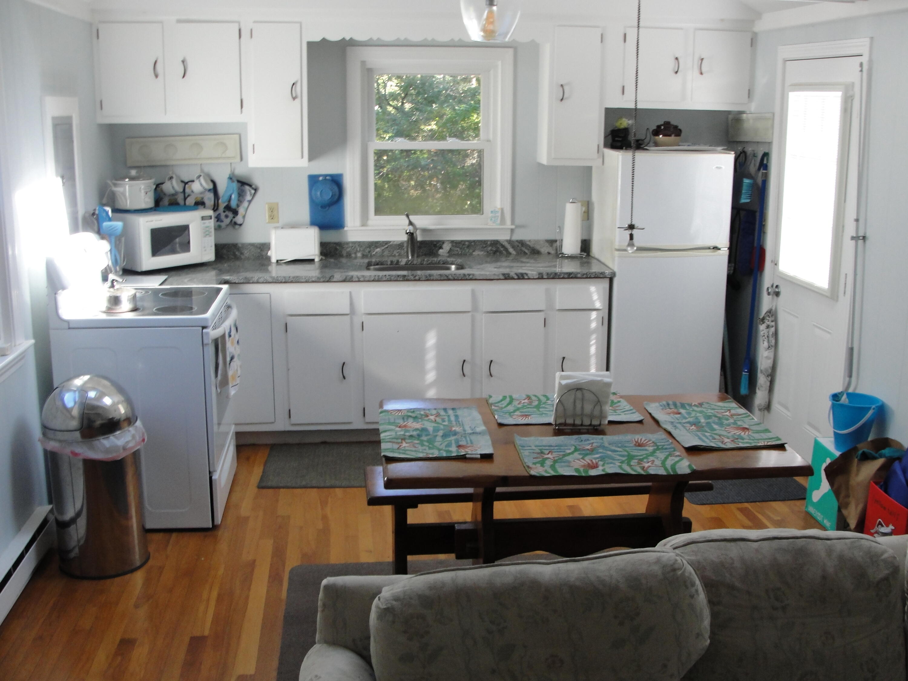 7 E Toms Path Dennis Port, MA 02639 - Photo 2 of 26 a kitchen with stainless steel appliances granite countertop a sink dishwasher a refrigerator and a dining table with wooden floor