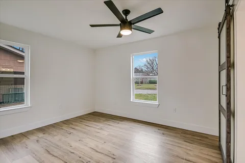 a view of empty room with wooden floor and fan