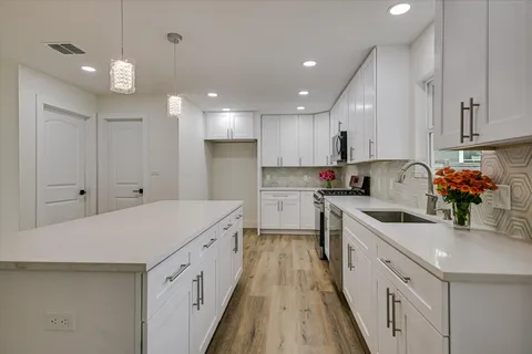 a kitchen with white cabinets sink and stove