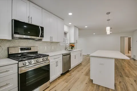 a kitchen with a stove a microwave and white cabinets