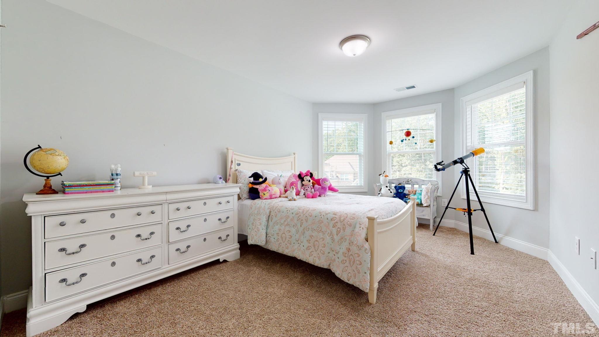 2351 Terrmini Drive Apex, NC 27502 - Photo 25 of 30 a bedroom with a bed and a chandelier