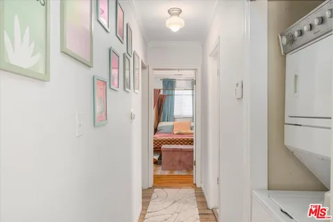 a view of a hallway with wooden floor and a bathroom
