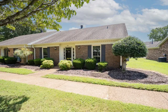 a front view of a house with a yard and potted plants