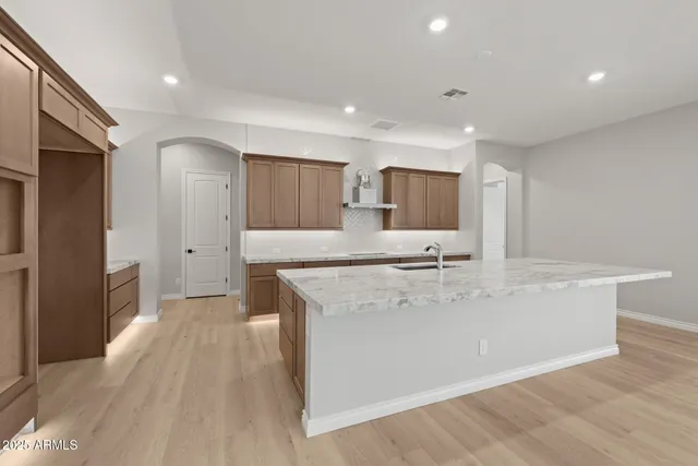 a large kitchen with stainless steel appliances granite countertop a large counter top and a wooden floors