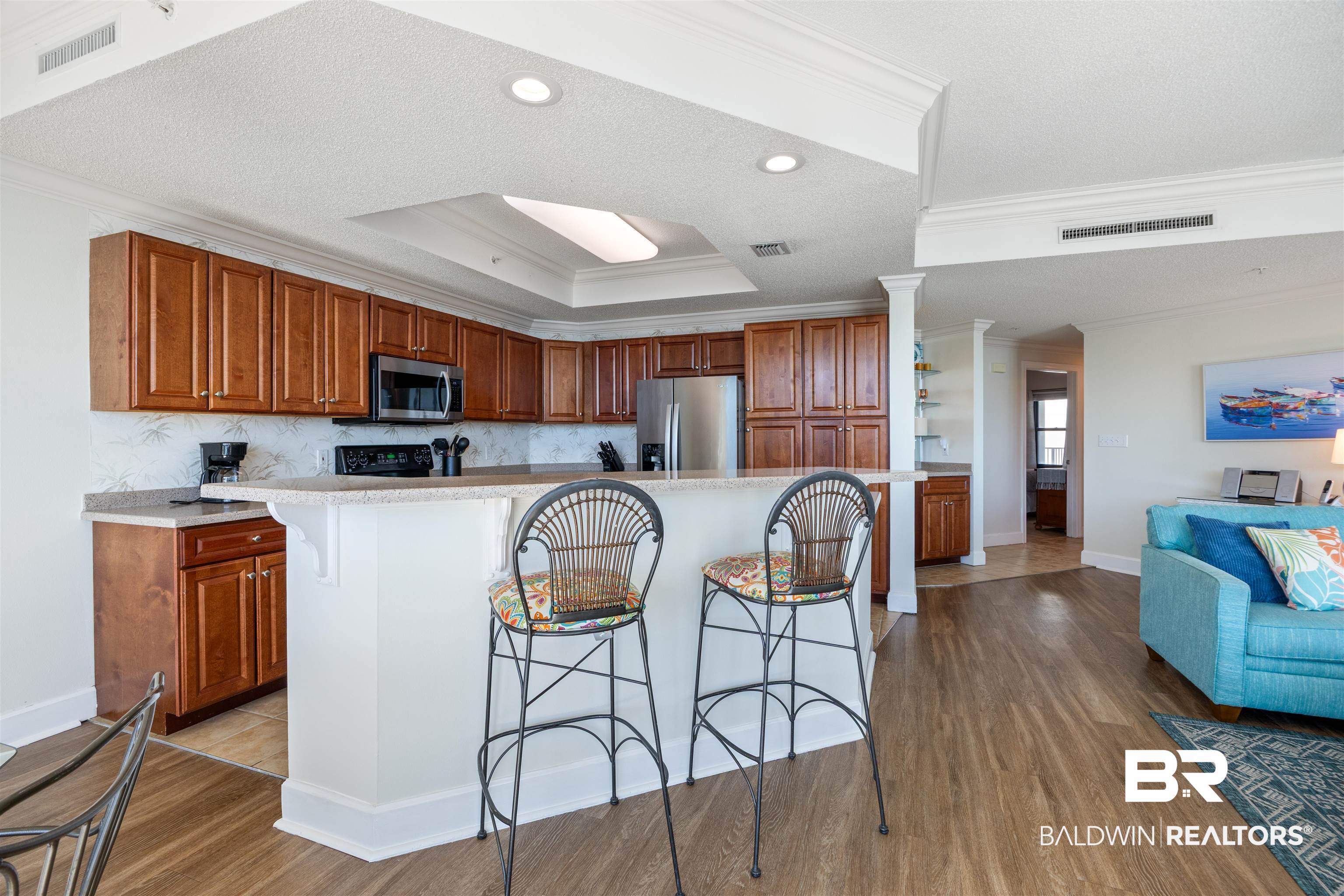 27580 Canal Road, Unit 1431 Orange Beach, AL 36561 - Photo 15 of 73 Kitchen with brown cabinets, a kitchen bar, crown molding, dark wood-style flooring, and recessed lighting