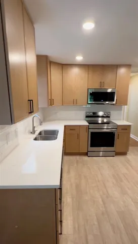 a kitchen with stainless steel appliances a sink a stove a microwave a sink a refrigerator and cabinets