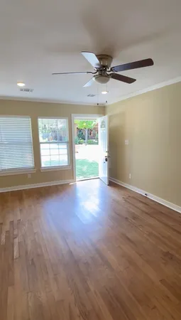 an empty room with wooden floor and windows