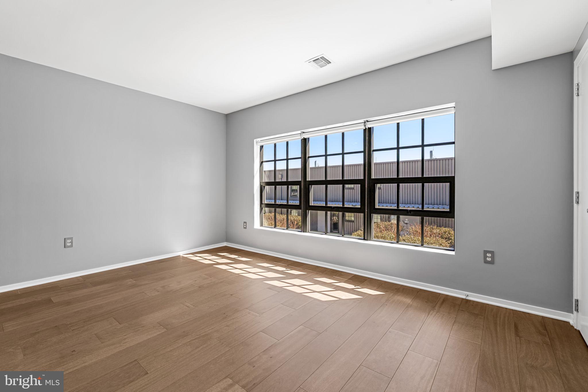 1200 Steuart Street, Unit 1035 Baltimore, MD 21230 - Photo 37 of 96 a view of an empty room with a window and wooden floor