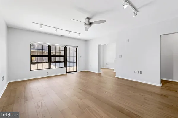 an empty room with wooden floor chandelier and windows