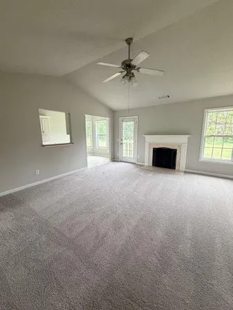 a view of an empty room with a window and fireplace