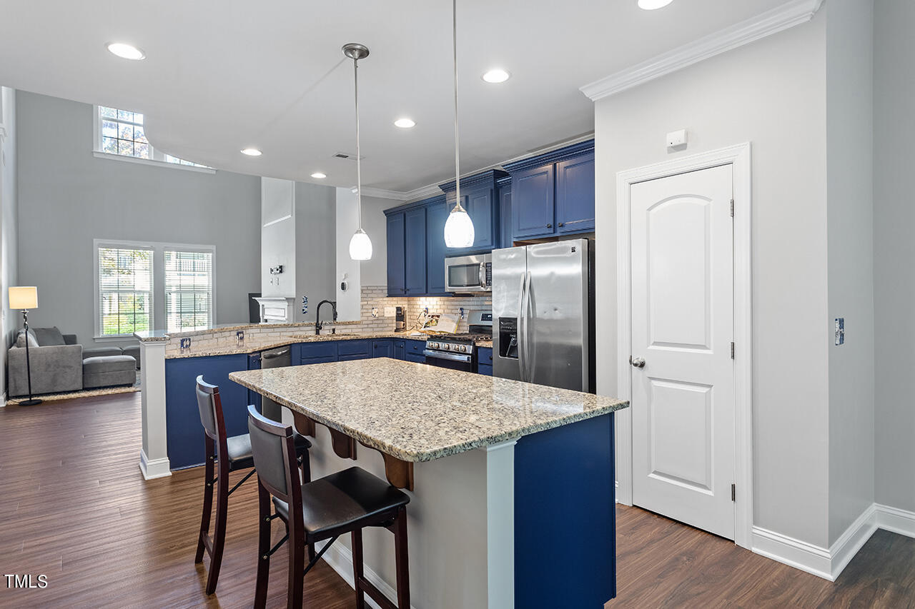 1337 Formal Garden Way Raleigh, NC 27603 - Photo 14 of 36 a kitchen with stainless steel appliances granite countertop a refrigerator a sink dishwasher a dining table and chairs with wooden floor