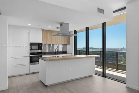 a view of kitchen with stainless steel appliances wooden floor and window