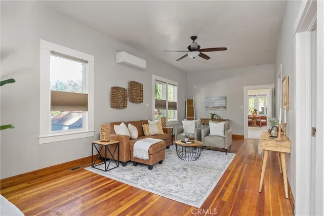 a living room with furniture two windows and wooden floor