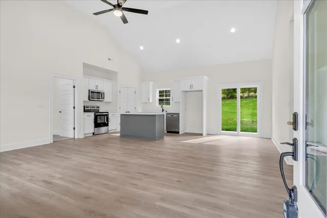 a view of an empty room with a window and kitchen view