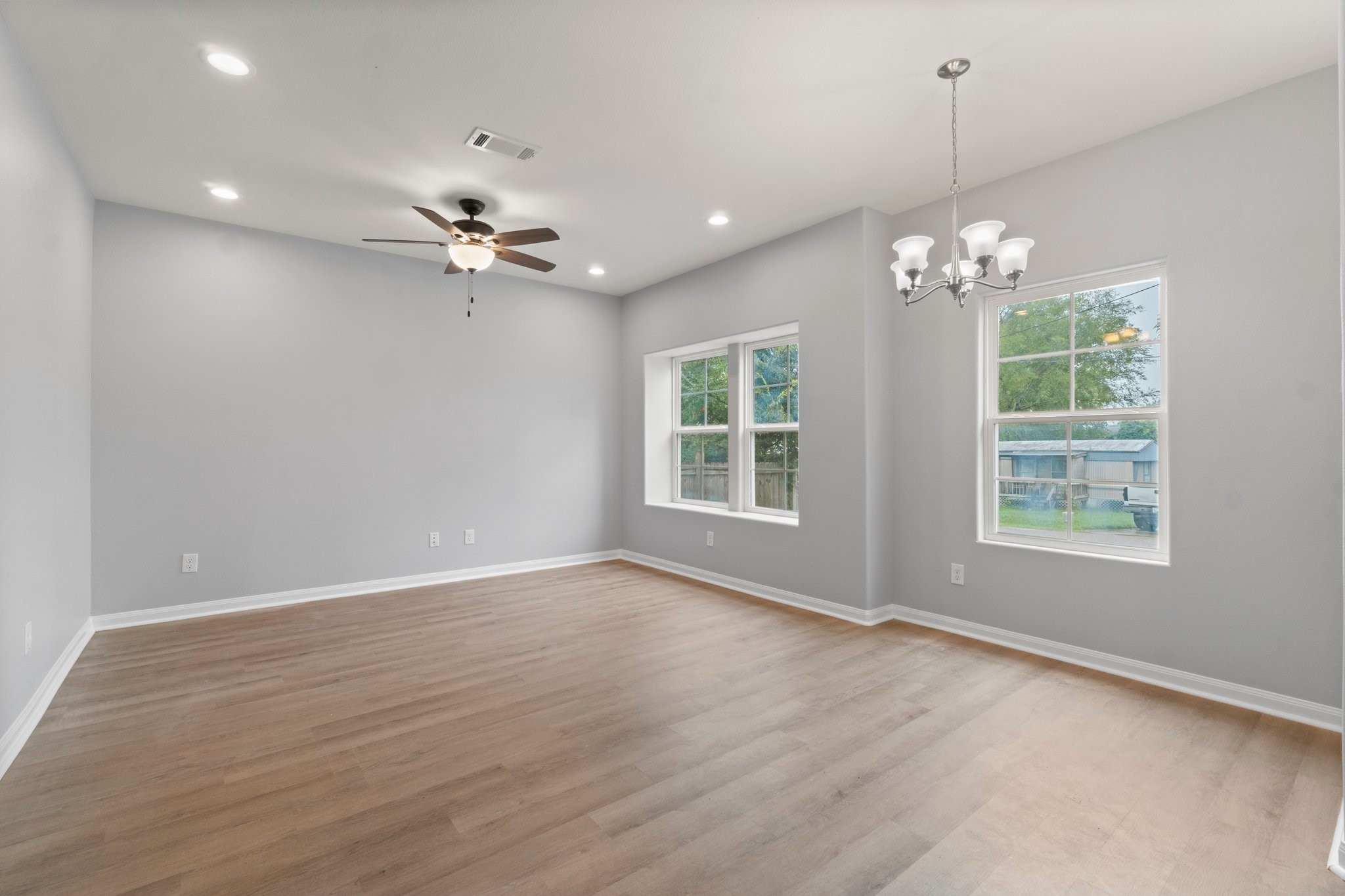 16866 West Hammon Montgomery, TX 77316 - Photo 4 of 21 an empty room with wooden floor chandelier fan and windows
