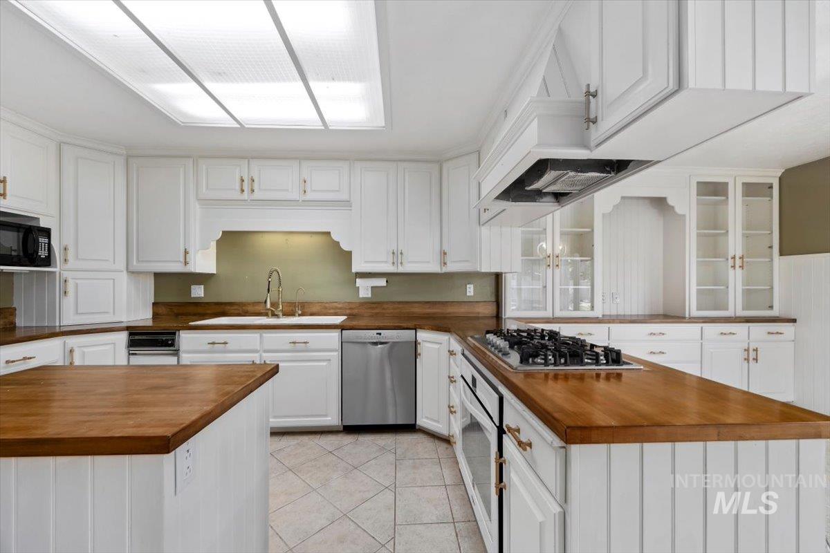 813 7th Street Rupert, ID 83350 - Photo 19 of 48 Spacious kitchen featuring extensive wood-finish countertops, white cabinetry with gold-tone hardware, and a center island with a built-in cooktop