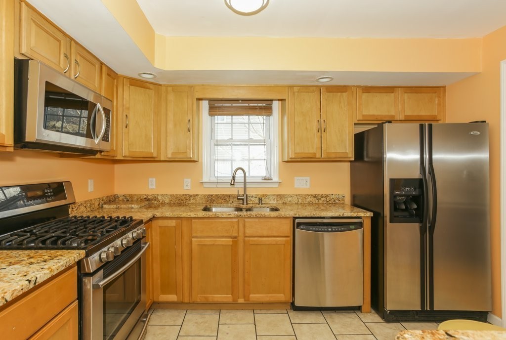 2-6 Guild Street, Unit 4 Boston, MA 02119 - Photo 4 of 20 a kitchen with stainless steel appliances granite countertop a stove a sink and a refrigerator