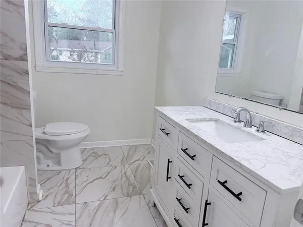 a bathroom with a granite countertop sink mirror vanity and toilet