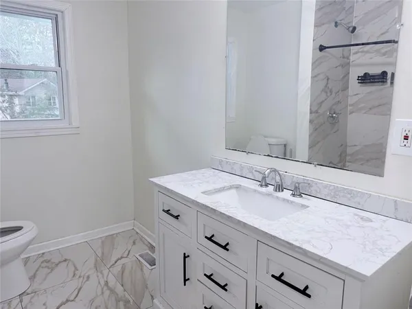 a bathroom with a granite countertop sink mirror vanity and toilet