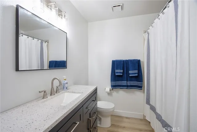 a bathroom with a granite countertop sink a toilet and a mirror