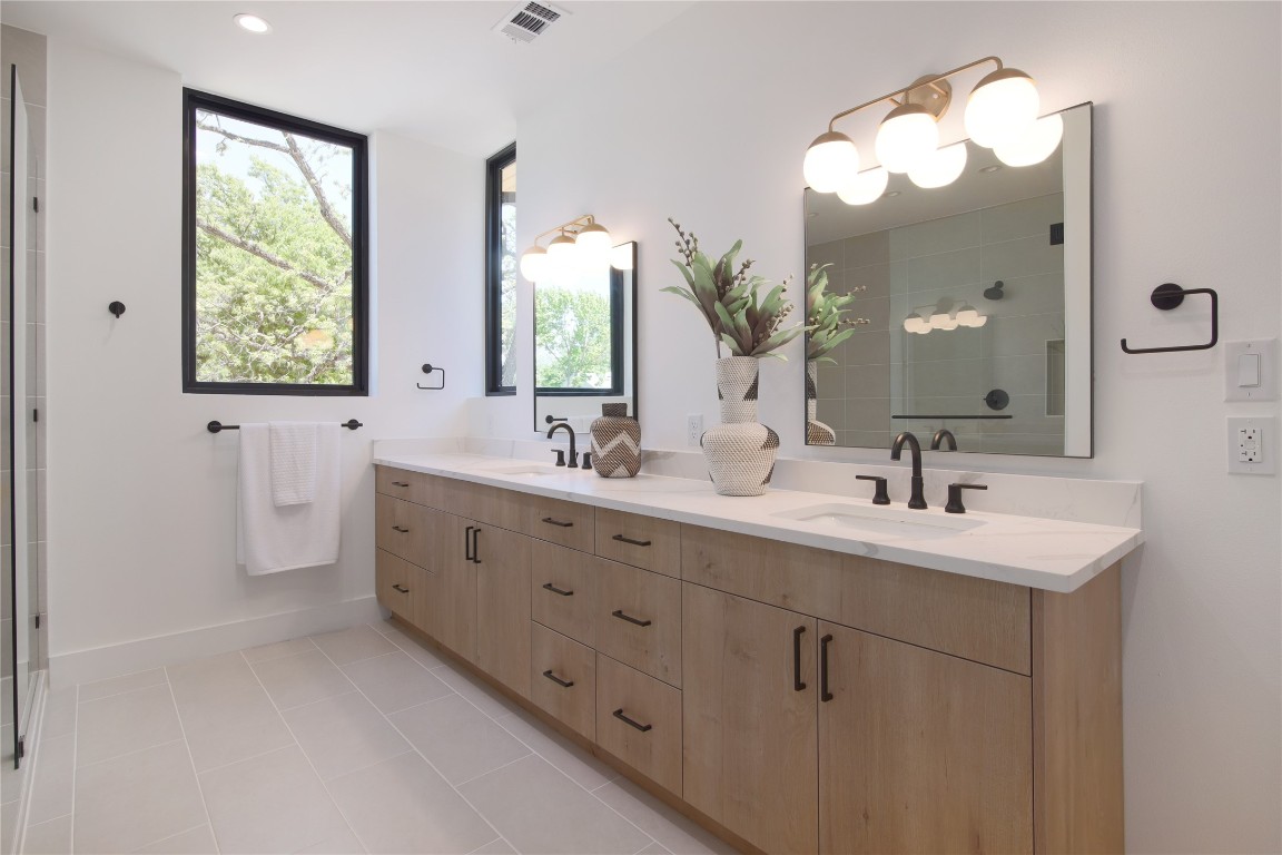 2401 Willow Street Austin, TX 78702 - Photo 21 of 38 a bathroom with double vanity sink a two mirror a window a vanity and a bathtub