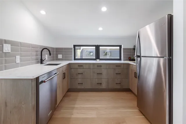 a kitchen with stainless steel appliances granite countertop a refrigerator a stove and a sink