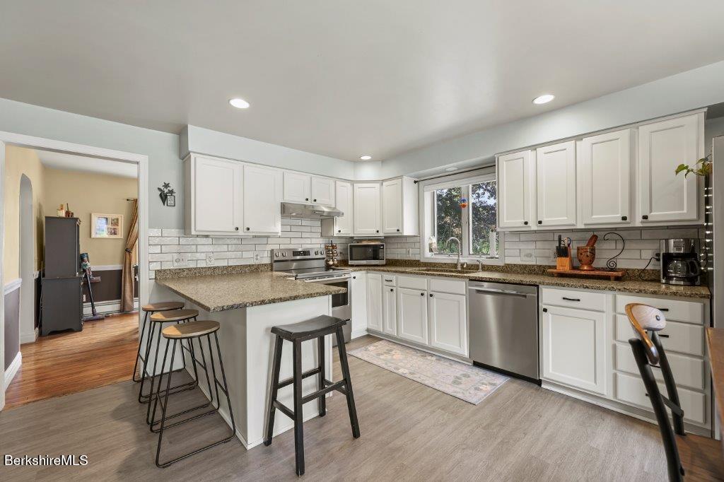 33 Eleanor Road Pittsfield, MA 01201 - Photo 13 of 45 a kitchen with stainless steel appliances granite countertop a stove a sink a refrigerator and white cabinets with wooden floor