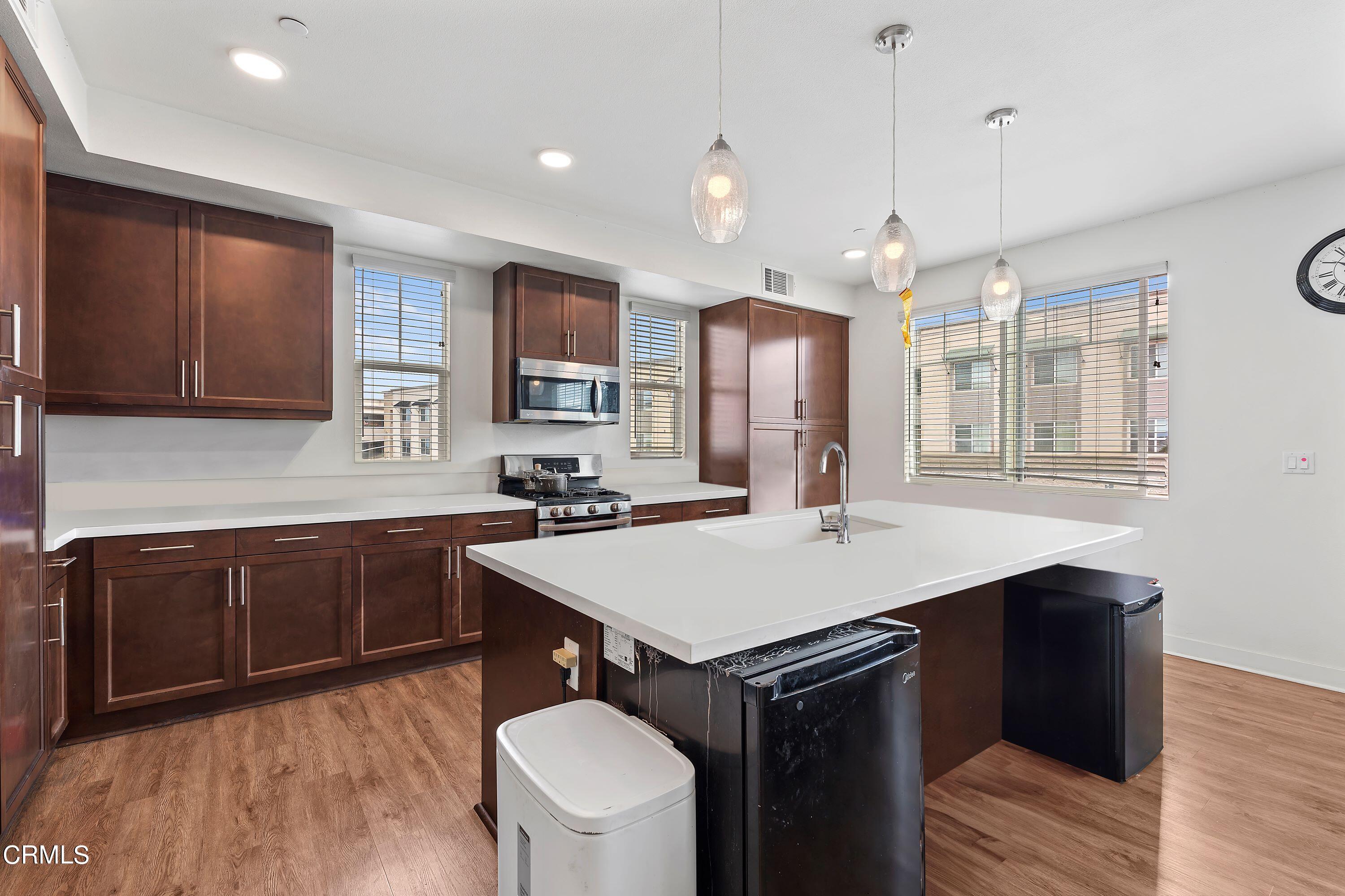 2800 Wagon Wheel Road, Unit 302 Oxnard, CA 93036 - Photo 8 of 28 a kitchen with a stove a sink dishwasher a kitchen island with wooden cabinets and floor