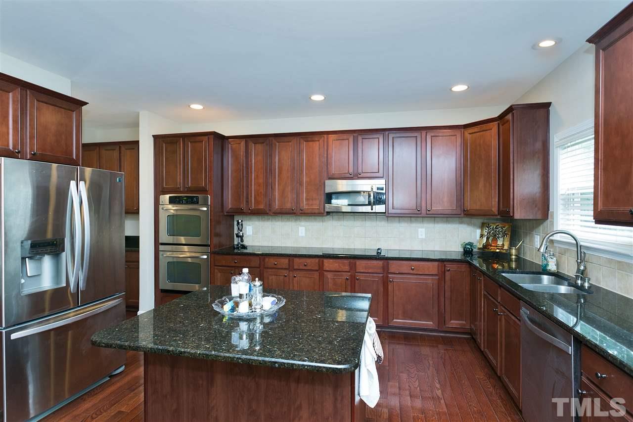 119 Key Biscayne Court Raleigh, NC 27603 - Photo 7 of 24 a kitchen with kitchen island granite countertop a sink refrigerator and cabinets