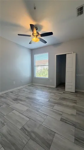 an empty room with windows and fan